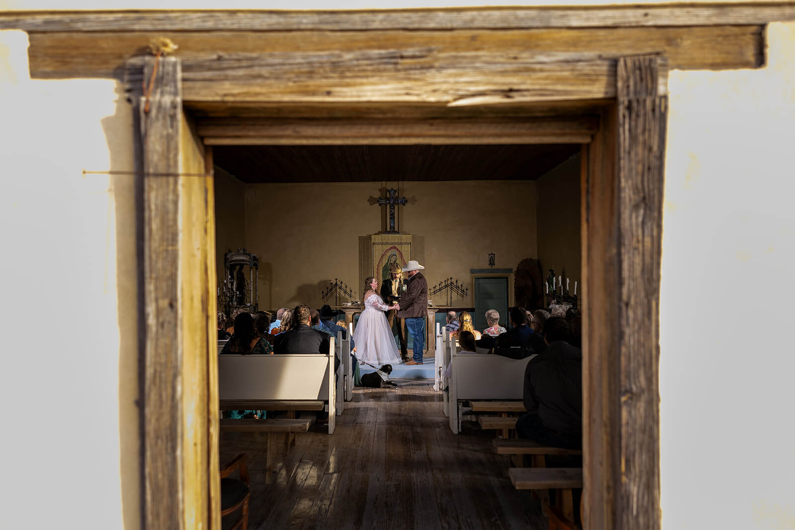 Couple moments away from saying I Do in Saint Agnes Church in Terlingua Ghost Town, Texas with friends and family in the pews witnessing this love story.